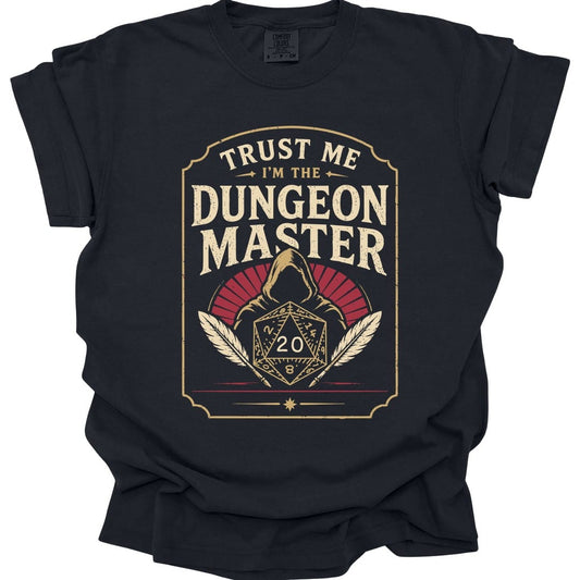 Black t-shirt. A tall cream badge with a ruled border. "Trust me" sits at the top, then "Dungeon Master" in large capitals. Below, a hooded figure looms behind a twenty-sided die showing 20, flanked by two quill feathers, with a dark red fan behind the hood. Vintage badge style in cream and deep red.