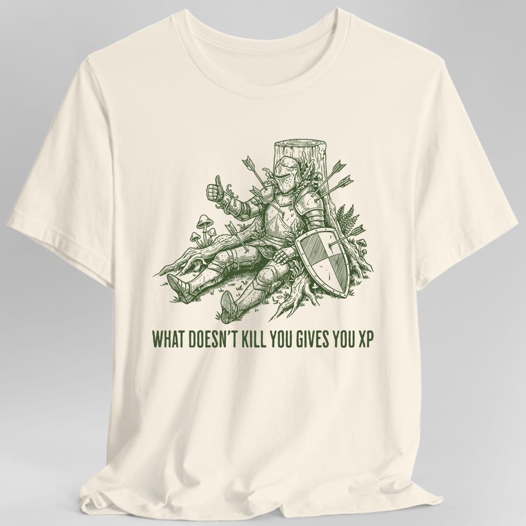 Natural t-shirt. An armored knight sits slumped against a tree stump with six arrows sticking out of him, still cheerfully giving a thumbs up, his kite shield propped at his side. Ferns, mushrooms and tree roots grow around him. Below, "What Doesn't Kill You Gives You XP" runs in tall condensed capitals. Single color forest green woodcut line art.
