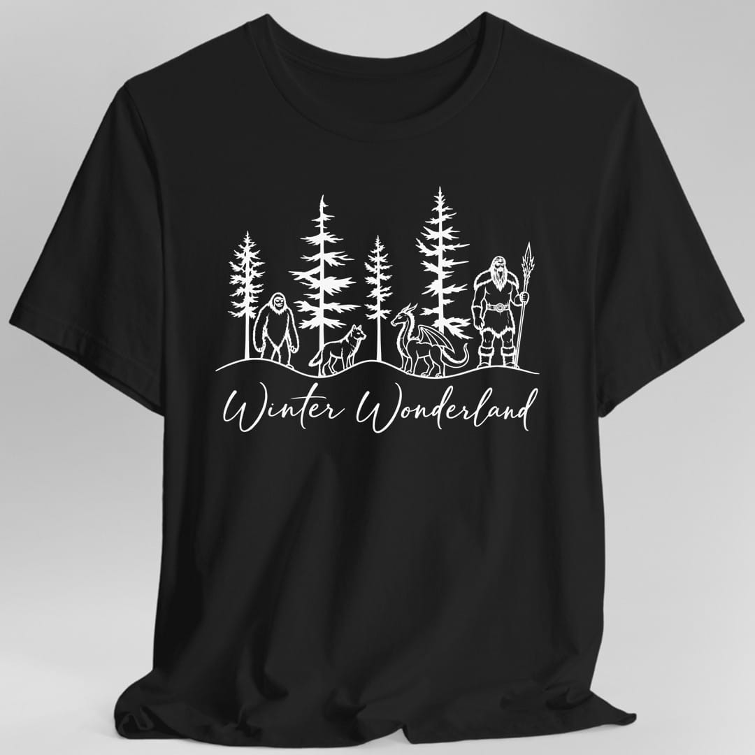 Black t-shirt. White line art. Five tall pine trees stand along a snowy ridge. In front of them, left to right, a shaggy yeti, a wolf, a small winged dragon and a bearded giant in furs holding a spear. Below the ridge the words "Winter Wonderland" run across the design in large flowing handwritten script.